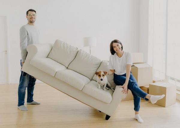 На фото – семейная пара передвигает диван